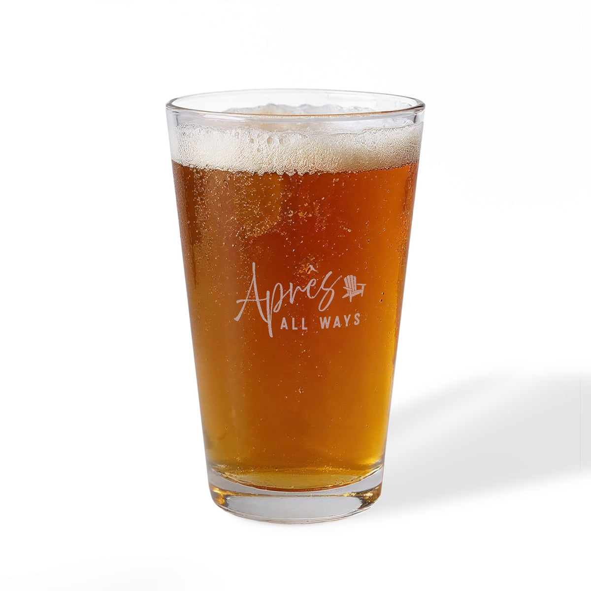 A clear pint glass filled with amber beer and topped with white foam, featuring the white etched text 'Apres ALL WAYS' on the front, set against a clean white background.