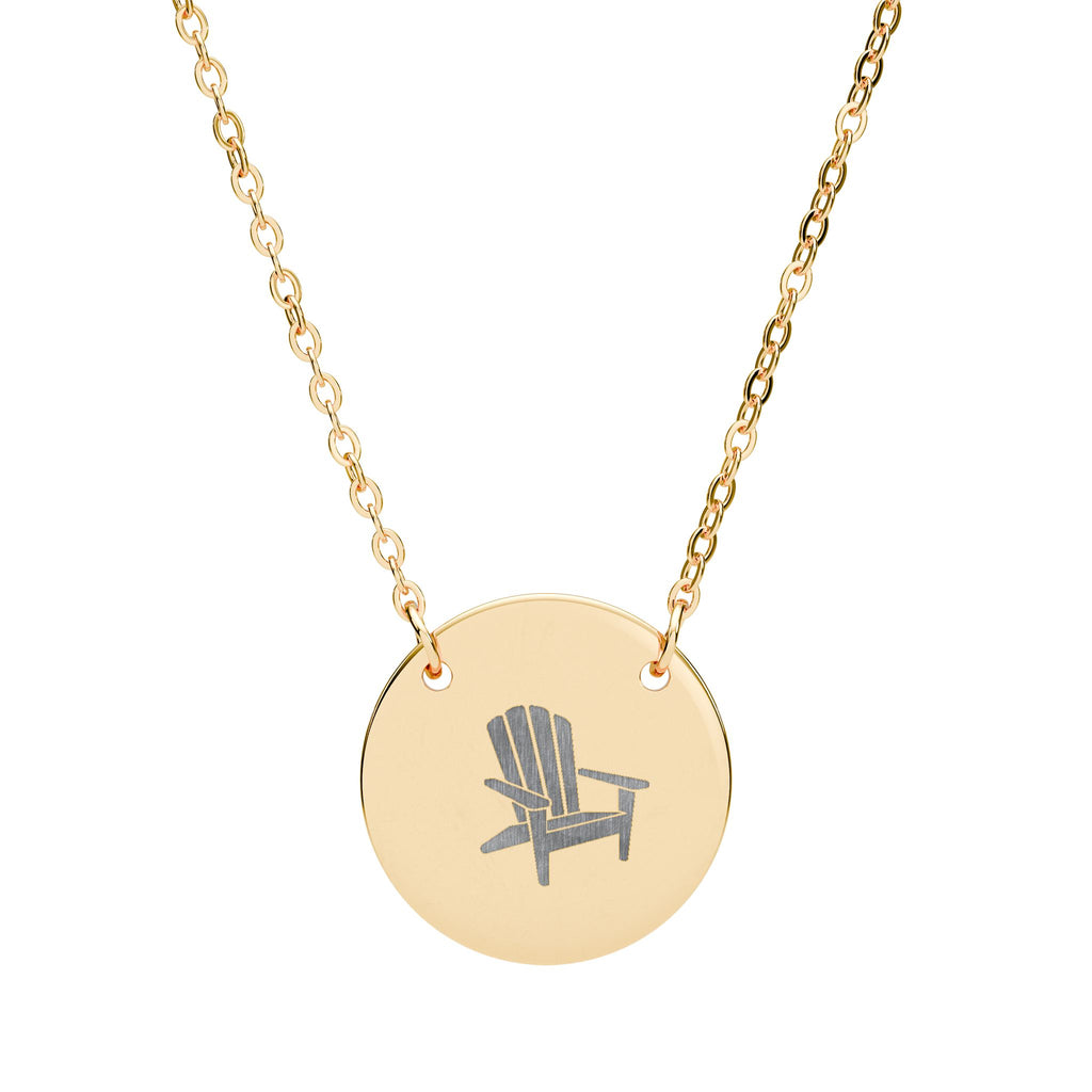 Après All Ways gold necklace with a round pendant engraved with an Adirondack chair, suspended from a delicate oval-link chain on a white background.