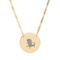 Après All Ways gold necklace with a round pendant engraved with an Adirondack chair, suspended from a delicate oval-link chain on a white background.