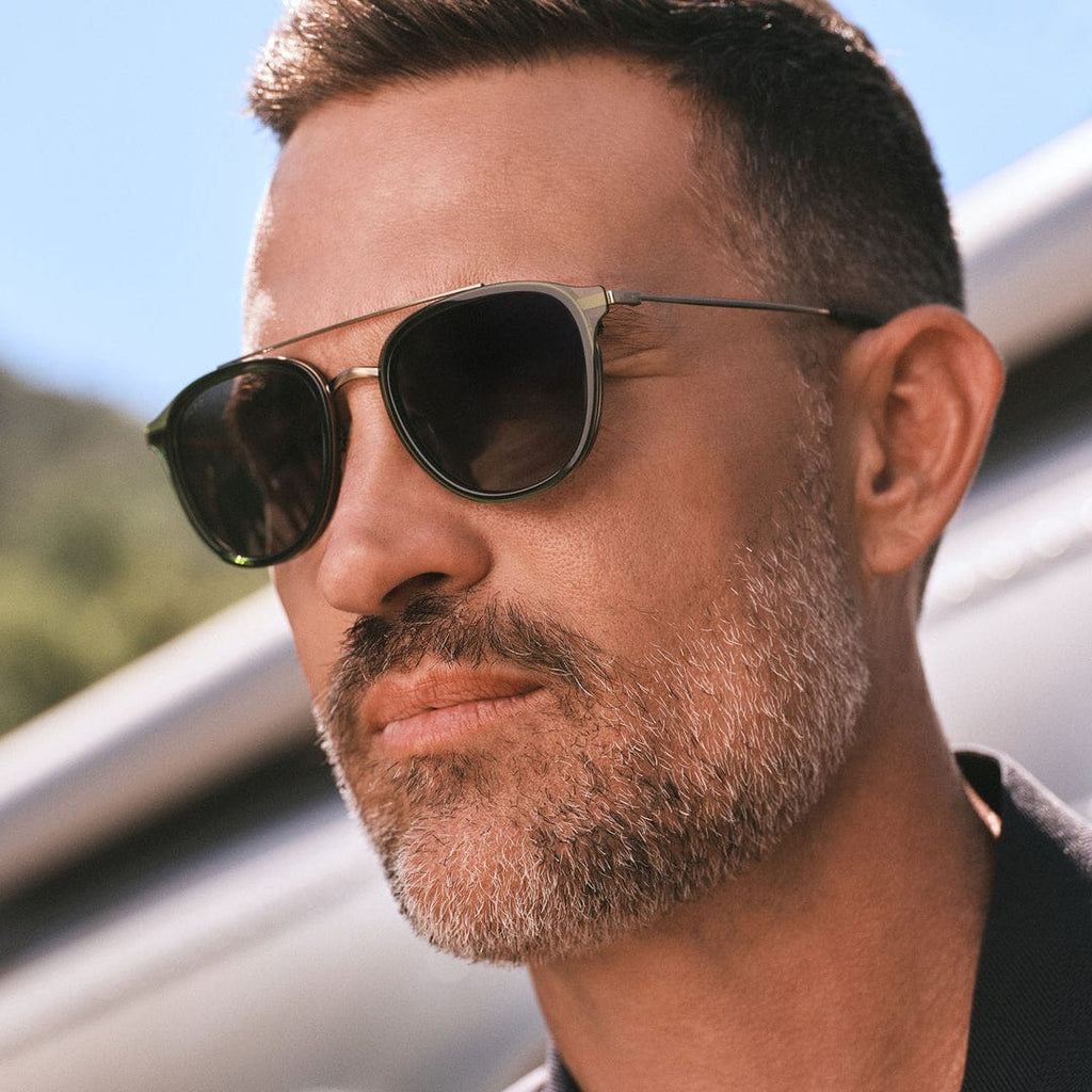 Man wearing Camden by DIFF polarized sunglasses with dark lenses and metal aviator-style frames outdoors under a blue sky.