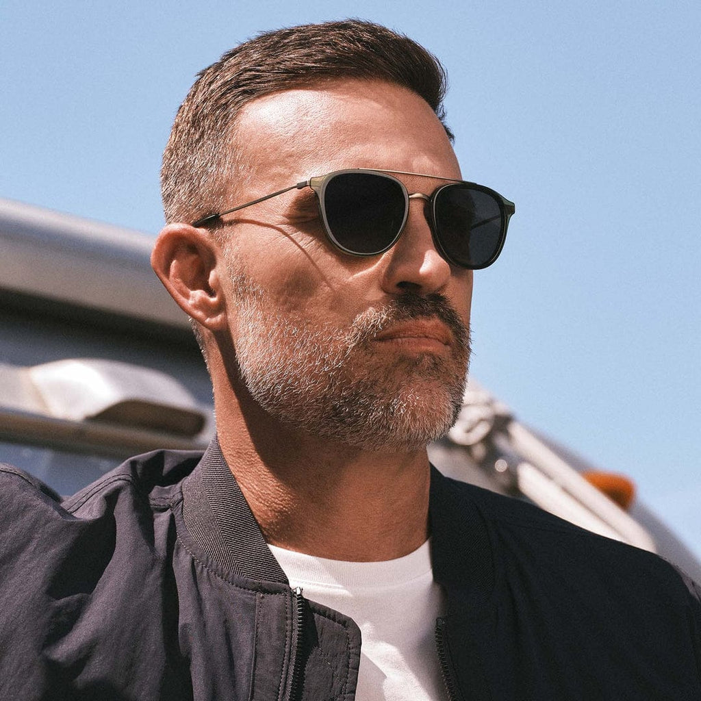 Man wearing Camden by DIFF polarized sunglasses with dark lenses and metal aviator-style frames outdoors under a blue sky.