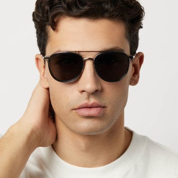 Man wearing Camden by DIFF polarized sunglasses with dark lenses and metal aviator-style frames in front of white background